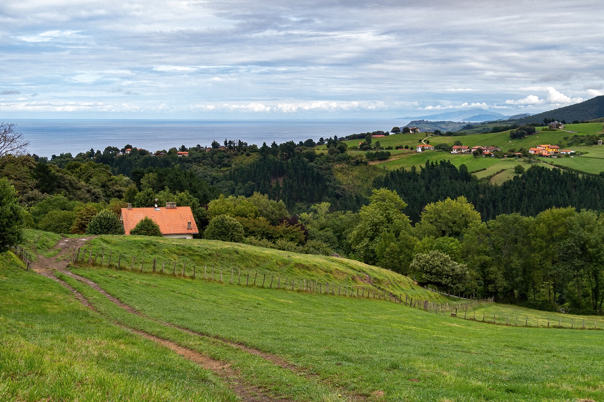 Zdjęcie przedstawiające krajobraz, na którym znajdują się domy, wzgórza i morze